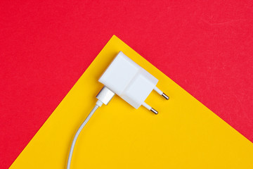Charger with cable on red-yellow background. Top view