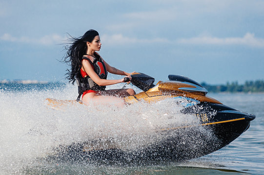 Athletic brunette rides a jet ski at sea