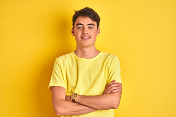 Fototapeta premium Teenager boy wearing yellow t-shirt over isolated background happy face smiling with crossed arms looking at the camera. Positive person.