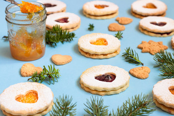 Linzer Christmas or New Year cookies filled with jam and dusted with sugar on blue paper background. Traditional Austrian Christmas cookies. Festive decoration.