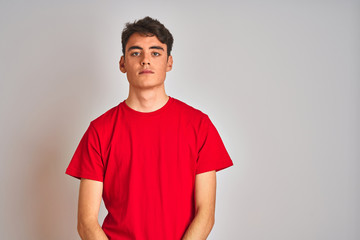 Teenager boy wearing red t-shirt over white isolated background with serious expression on face. Simple and natural looking at the camera. - Powered by Adobe