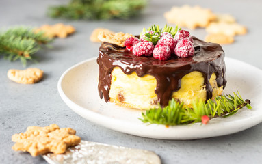 Delicious New York cheesecake with chocolate ganache, raspberries and cookies with fir branches. Festive decoration. 