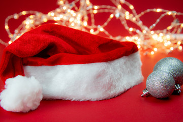 Czapka MIkołaja oraz srebrne bombki na tle światełek © andsko
