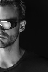 Obraz premium Black and White Muscle strong beautiful stripped male model with white black t-shirt and glasses eyewear on black isolated font background