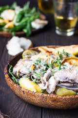 Chicken thighs roasted with apples and cider on a dark brown wooden table. Fall dinner recipe. Comfort food.
