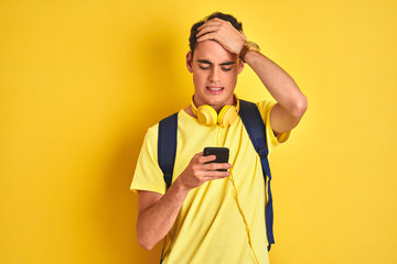 Teenager boy wearing headphones and using smartphone over isolated background stressed with hand on...