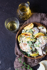 Chicken thighs roasted with apples and cider on a dark brown wooden table. Fall dinner recipe. Comfort food.