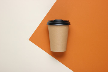 Craft cardboard coffee cup on a brown-beige paper background. Top view