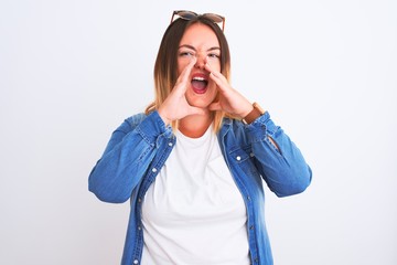 Beautiful woman wearing denim shirt standing over isolated white background Shouting angry out loud with hands over mouth