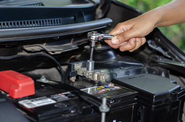 Naklejka premium A woman using a wrench to change the car battery