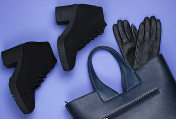 Leather bag, gloves and boots on purple paper background. Minimalistic fashion still life. Flat...