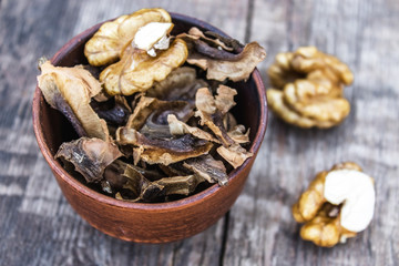 Walnut kernels and partitions in a bowl and whole walnuts on a wooden table. A medicine for tinctures and decoctions.