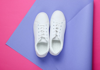 Stylish white sneakers on folded paper background. Minimalism fashion concept. Top view