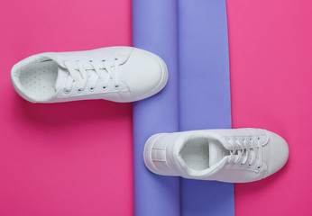 Stylish white sneakers on folded paper background. Minimalism fashion concept. Top view