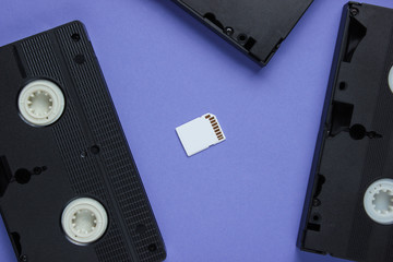 Obraz premium SD memory card, video cassette on purple paper background. Modern and obsolete storage for media. Top view