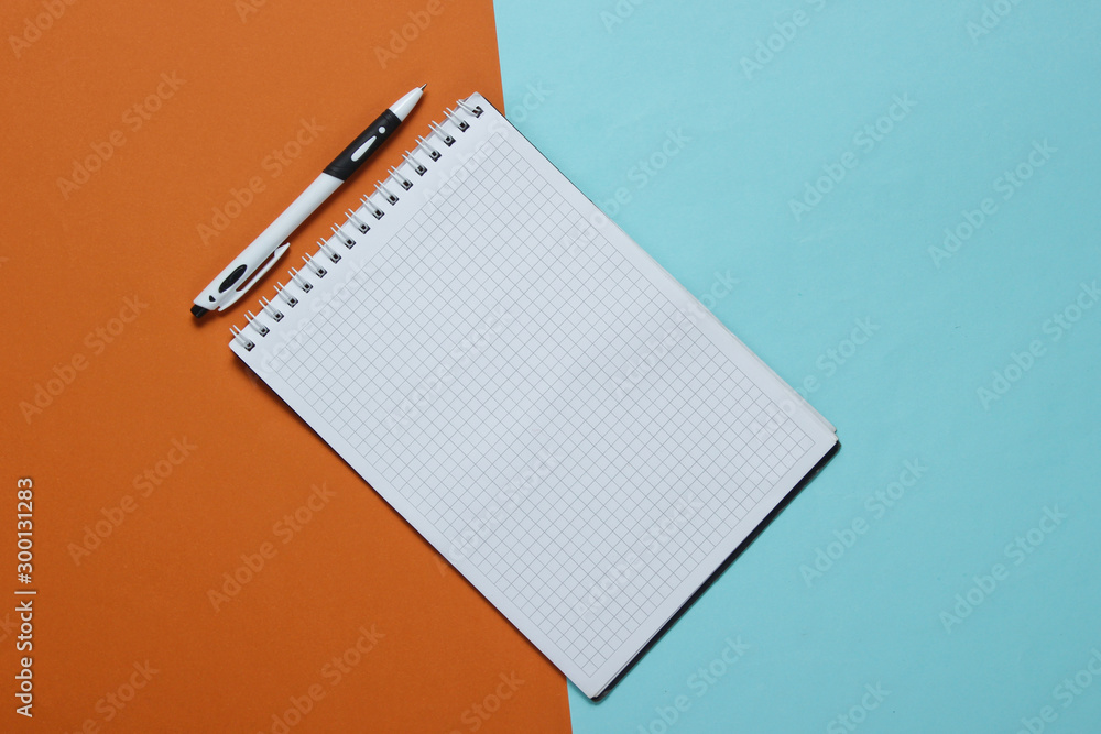 Aufkleber notebook with pen on color paper background. top view