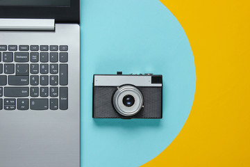 Laptop and retro camera on a blue-yellow background. Travel concept. Top view