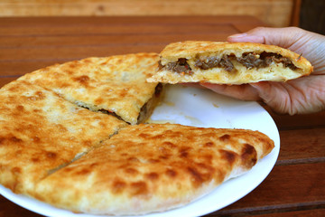 Woman's Hand Holding a Piece of Kubdari, Georgian Traditional Flat Bread Filled with Spiced Meat