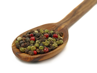 close up wooden spoon with pepper mix isolated on white background. Black, red, green and white peppercorns macro shot