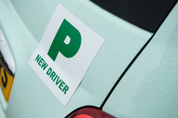 Newly fitted magnetic New Driver plate seen attached to the rear of a new, small Italian made car. Seen after a heavy downpour at a driving centre.