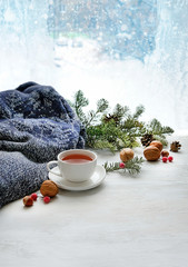 Cup of tea, nuts and sweater on background of winter frost window. sweater weather, cozy home, winter season background. home comfort in snowy weather. new year, Christmas holiday. soft focus