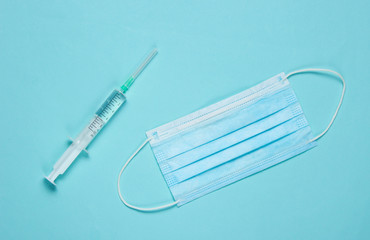 Medical still life on a blue background. Syringe, medical mask. Minimalism