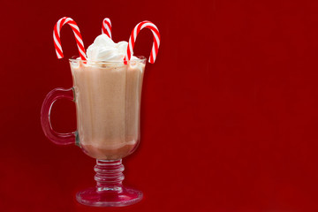 Glass of hot cocoa with marshmallows and Christmas candies on a red background.Concept Christmas drinks concept. Copy space.