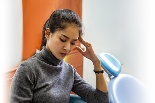 portrait of stressed sad sick woman with headache; ill woman suffers from vertigo, dizziness, migraine, hangover, health care depression emotional concept; young adult asian woman model