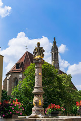 Vertical view of the beautiful fountain of Heron Brunnen whose bottom is the Franciscan Church of the town. Photograph taken in Rothenburg ob der Tauber, Bavaria, Germany