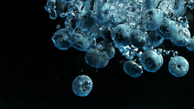 Super Slow Motion Shot of Falling Blueberries Into Water Isolated on Black Background at 1000fps.