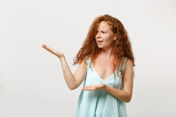 Young bewildered redhead woman girl in casual light clothes posing isolated on white background studio portrait. People sincere emotions lifestyle concept. Mock up copy space. Pointing hands aside.