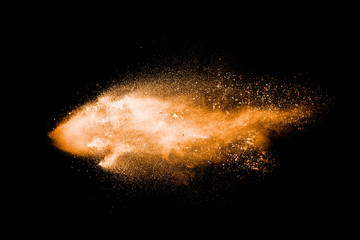 Fototapeta na wymiar Abstract orange powder explosion on black background. Freeze motion of orange dust particles splash.