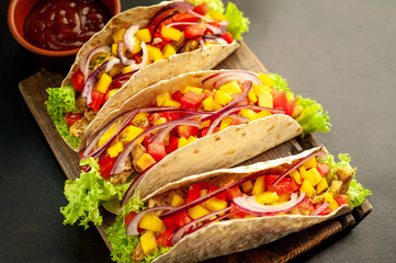 Mexican tacos with meat and vegetables on a stone background