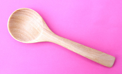 wooden spoon isolated on a pink background.