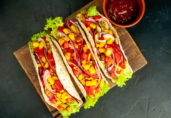 Mexican tacos with meat and vegetables on a stone background