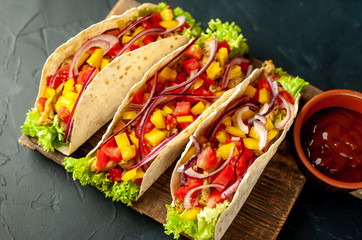 Mexican tacos with meat and vegetables on a stone background