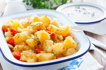 Baked sliced potatoes with carrots and onions in an enameled form, horizontal