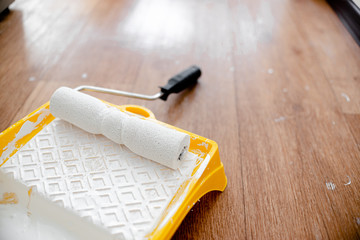 Painting roller with white paint in yellow box. Horizontal view copyspace. House repair concept