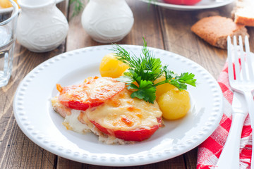 Baked pink salmon with tomato and cheese on a white plate with potatoes, horizontal