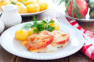 Baked pink salmon with tomato and cheese on a white plate with potatoes, horizontal