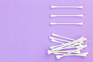 Cotton ear buds layed out in still life on a paster violet background with copy space