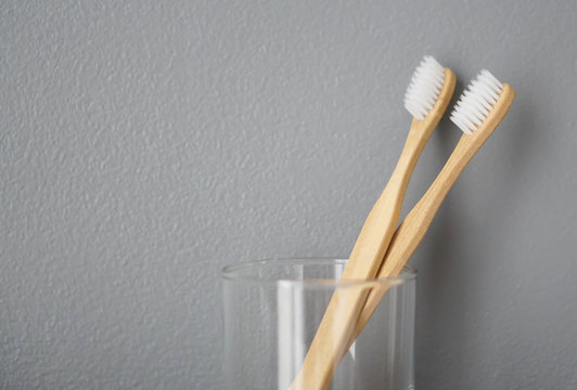 Close up wooden toothbrush in glass with grey background, selective focus