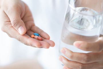 Obraz na płótnie Canvas Closeup woman hand holding pills and glass of water, health care and medical concept, selective focus