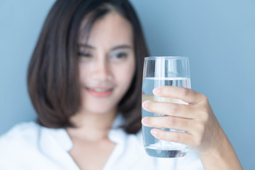 Close up woman hand holding glass of pure water with smile face background, Selective focus