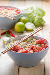 Instant noodles with sausage in bowl on wooden table