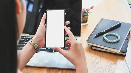 Cropped shot woman holding her smartphone with isolated white screen.