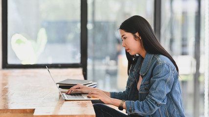 Young woman using laptop computer with campus concept.