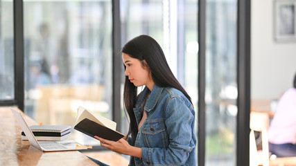 Fototapeta premium Young woman taking note on notebook paper in campus.