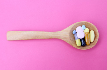 Medicine in wooden spoon isolated on a pink background.