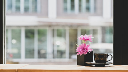 Coffee cup and flower pot on wooden table with copy space.